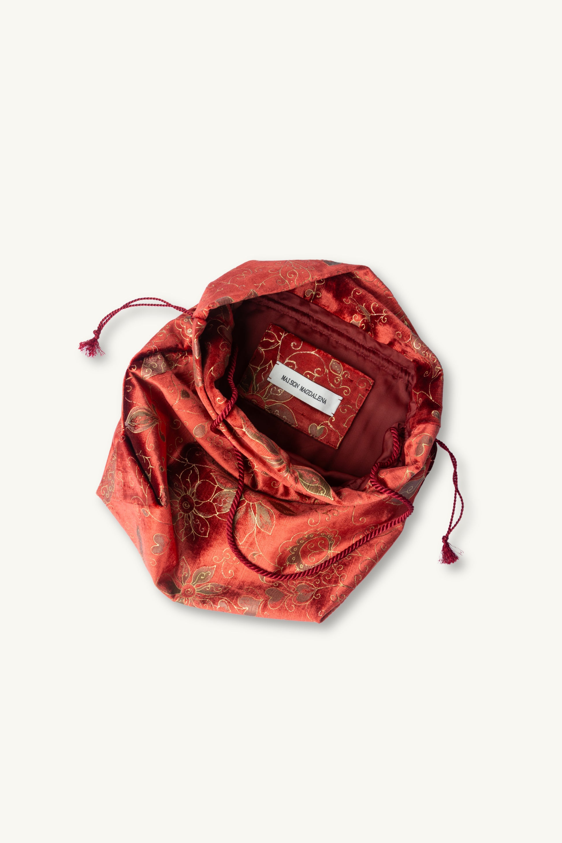 A red drawstring pouch with a gold floral patterned silk-like exterior and a dark red satin lining, shown on a light off-white background.